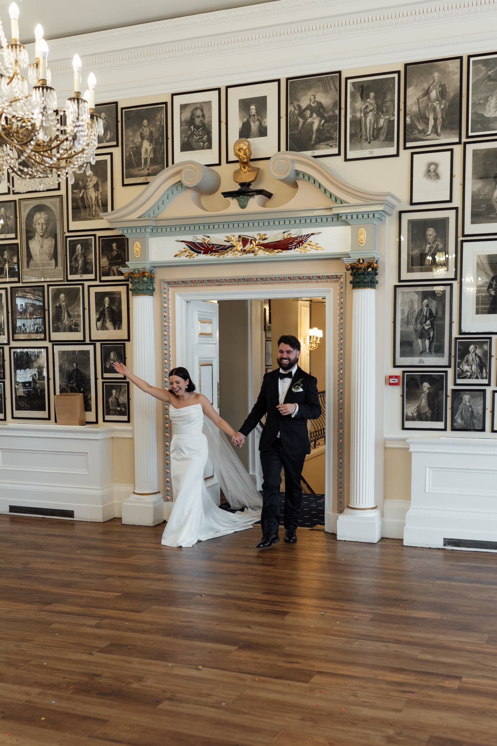 Kirsty and Jamie entering their Trafalgar Tavern reception while guests cheer around them